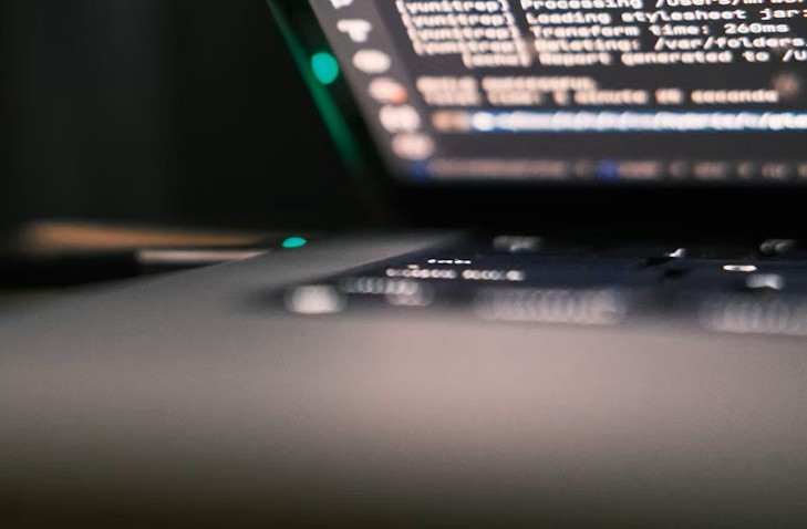 Software services visual - Close-up of a laptop screen showing code, with the keyboard blurred in the foreground.